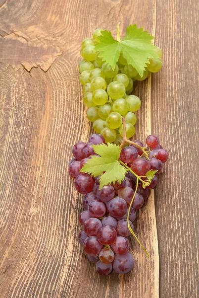 Uva con foglie su tavolo di legno — Foto Stock
