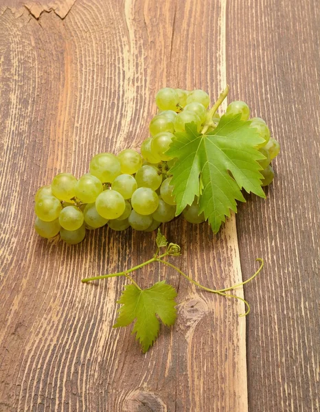 Uvas con hojas sobre mesa de madera —  Fotos de Stock