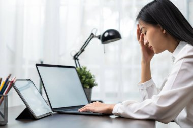 Asyalı iş kadını bilgisayarlarla çalışmaktan uzun süredir baş ağrısı çekiyor..
