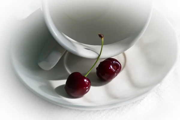 Reife Kirsche auf einem weißen Teller mit einer Tasse — Stockfoto