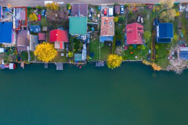 Szigetszentmiklos, Macaristan - Budapeşte yakınlarındaki Kavicsos Gölü 'nde (Kavicsos to) küçük bir balıkçılık adasının insansız hava aracı görüntüsü. Ada balıkçı kulübeleri, rıhtımlar ve kulübelerle dolu. Sonbahar renklerini ısıt.