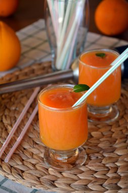 Ahşap bir masa üzerinde taze greyfurt, portakal ve papaya güler yüzlü iki kadeh. Portre.