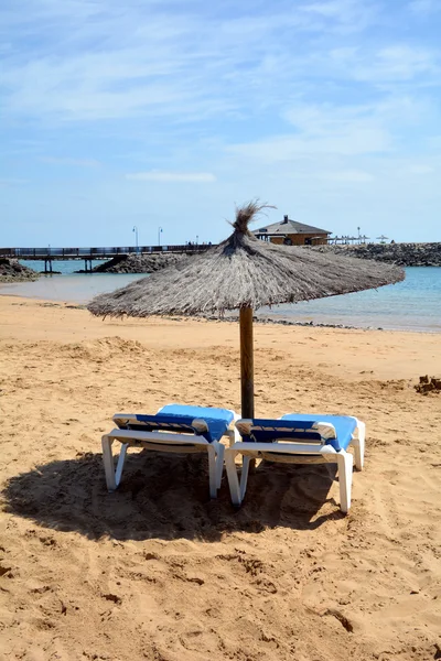 Cena com duas cadeiras de convés e guarda-chuva em uma praia tropical . — Fotografia de Stock