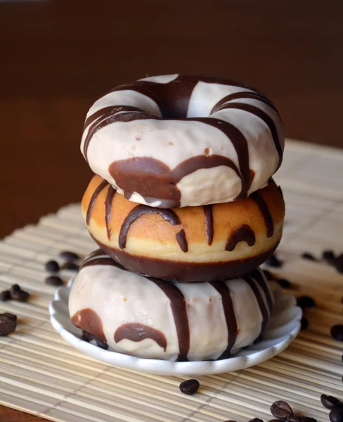 Традиционные пончики с коричневым шоколадом на тарелке на столе — стоковое фото