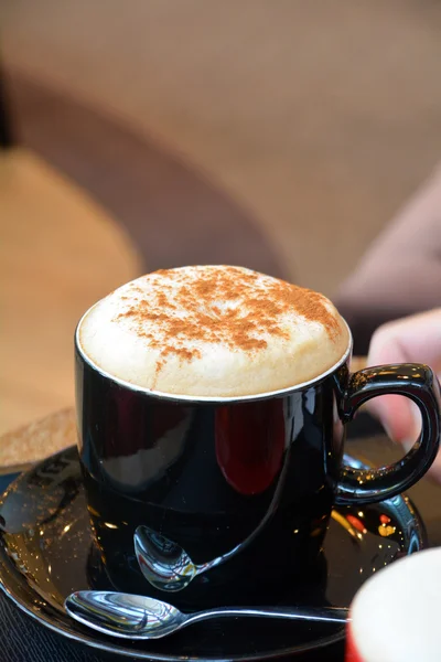 Cup of delicious foamy cappuccino on a plate — Stock Photo, Image
