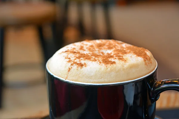 Copo de cappuccino espumoso delicioso em um prato — Fotografia de Stock