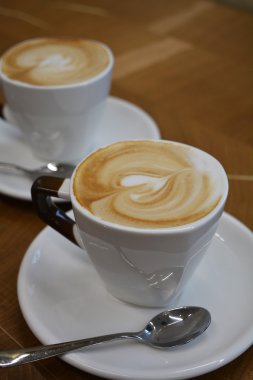 Ahşap bir masa üzerinde köpüklü kapuçino fincan