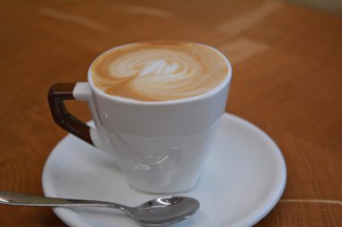 Ahşap bir masa üzerinde köpüklü kapuçino fincan