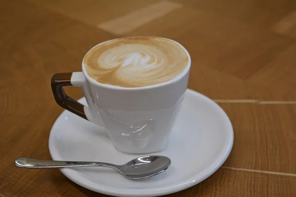 Xícara de cappuccino espumoso em uma mesa de madeira — Fotografia de Stock