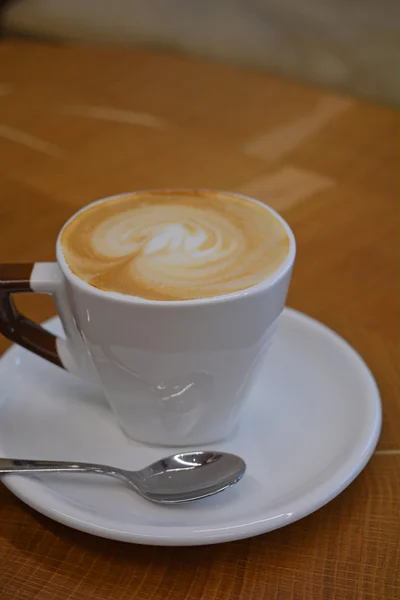 Copa de capuchino espumoso sobre una mesa de madera — Foto de Stock