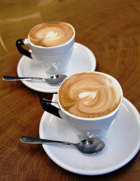 Delicious foamy cappuccino on a white cup on a plate — Stock Photo, Image