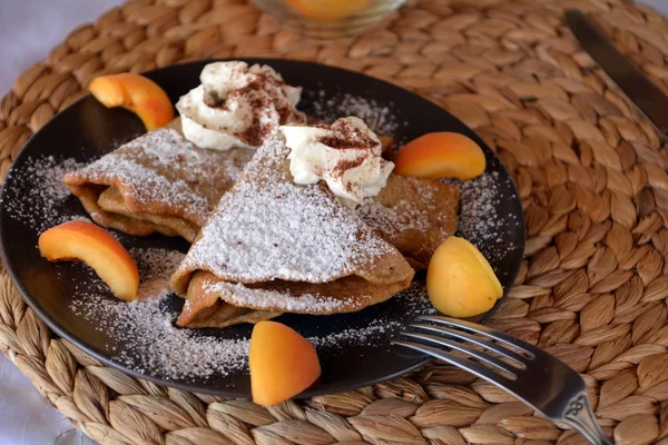 Crêpes maison sucrées avec confiture, abricots, crème fouettée et sucre glace . — Photo