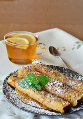 Çilek reçeli kahverengi tabak ve bardak çay ile tatlı krep. Krep