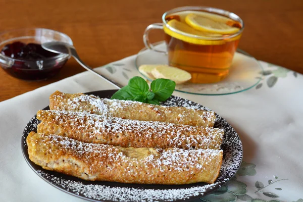 Sweet crepes with strawberry jam on the brown plate and cup of tea. Pancakes. — Stock Photo, Image