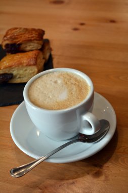 Fincan sıcak cappuccino ve ahşap masa üzerinde küçük pizza