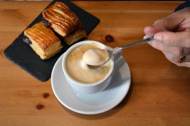 Adamın elini sıcak cappuccino ahşap masa üzerinde karıştırma