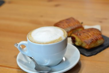 Ahşap masa üzerinde beyaz fincan lezzetli kapuçino