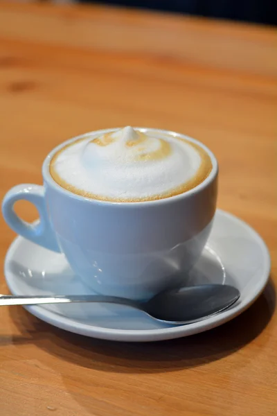 Απολαυστικό cappuccino σε λευκό Κύπελλο στο ξύλινο τραπέζι — Φωτογραφία Αρχείου