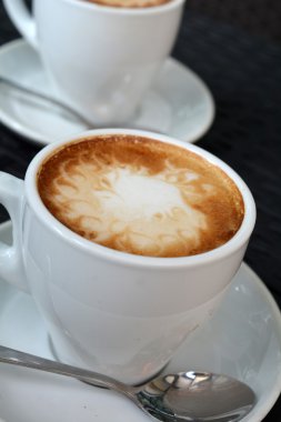 Siyah arka plan üzerine lezzetli sıcak cappuccino
