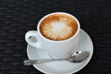 Siyah arka plan üzerine lezzetli sıcak cappuccino