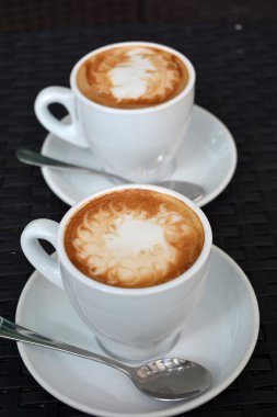 Siyah arka plan üzerine lezzetli sıcak cappuccino