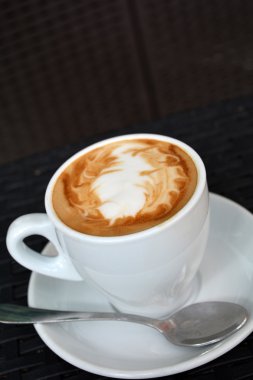 Siyah arka plan üzerine lezzetli sıcak cappuccino