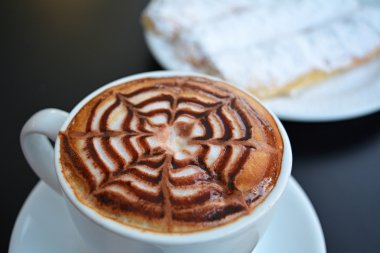 Fincan kapuçino ve siyah arka plan üzerine pasta