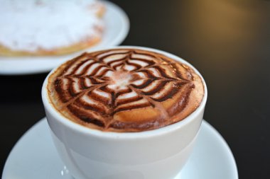 Kapuçino beyaz Kupası ve tatlı siyah arka plan üzerine