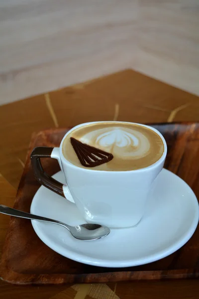 Taça de cappuccino delicioso em uma mesa de madeira — Fotografia de Stock