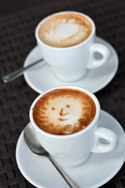 Tasse schäumenden Cappuccino mit Lächeln auf schwarzem Hintergrund — Stockfoto