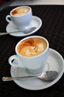 Siyah arka plan üzerine lezzetli köpüklü kapuçino fincan