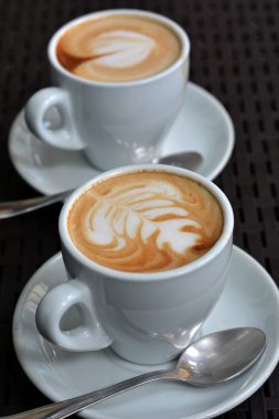 Köpüklü Cappuccino siyah bir zemin üzerine beyaz fincan