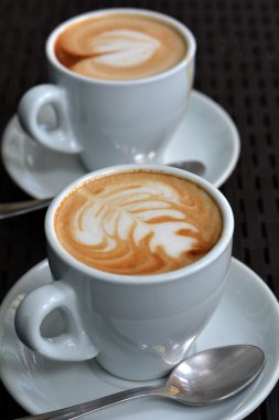 Köpüklü Cappuccino siyah bir zemin üzerine beyaz fincan
