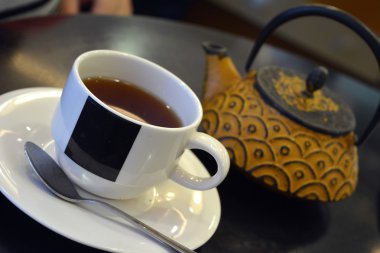 Siyah arka planda bir fincan çay ve çaydanlık.