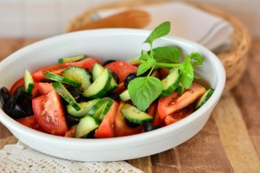 Salatalık ile sağlıklı sebze salatası, domates üzerinde beyaz bir porselen kase