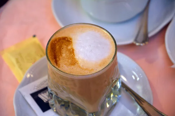 Pyszne cappuccino na szkło kubek na stole — Zdjęcie stockowe