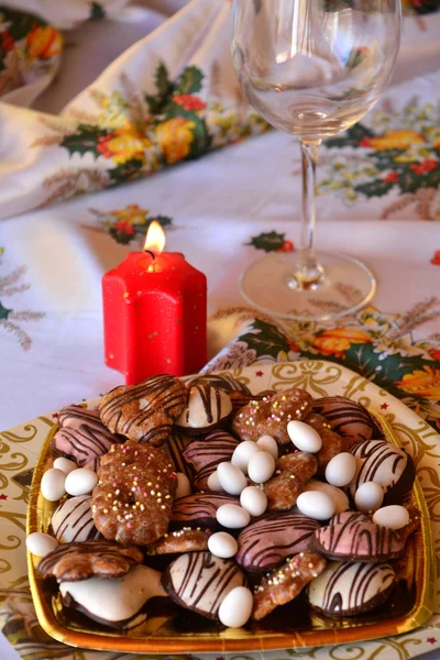 Detail von leckeren Weihnachtsplätzchen mit Kerzen in rotem Ton auf einem Tisch — Stockfoto