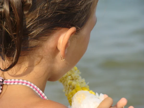 在海背景吃玉米的女孩 — 图库照片