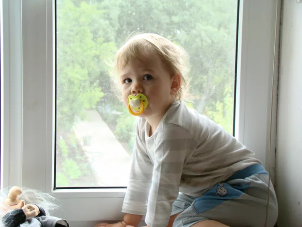 The child sits on the window — Stock Photo, Image