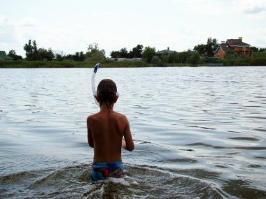 bir çocuk bir maske ve yüzme için şnorkel ile nehre banyoları.