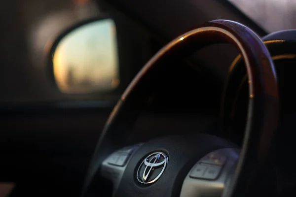 Gösterge paneli, medya sistemi, direksiyon ve vites ayarlı Toyota Camry 'nin siyah iç görüntüsü. Arabanın içindeki direksiyon simidini kapat. Toyota 'nın direksiyonu. 
