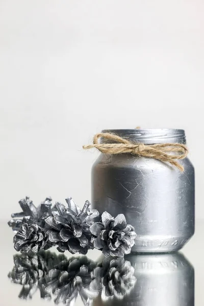 Haber Yılları Dekorasyonu. Diy. Yılbaşı mumları gümüş renginde, kendi elleriyle. Gümüş mum ve köknar kozalaklarının yakın çekimi. Yeni Yıl resmi