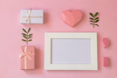Mesaj için fotoğraf çerçeveli düz yerde yatıyordu. Mutlu Anneler Günü, Kadınlar Günü, Sevgililer Günü ya da Doğum günü kartı. Pembe arka planda hediyeler ve kalp.