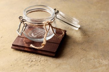 Boş cam kavanozu aç, arka plandaki tahta tezgahta şarjörü olan bir kapakla.