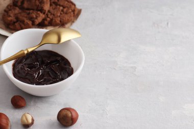 Çikolata fındığı, doğal fındıklı beyaz bir kaseye yayılmış. Altın kaşık, sağlıklı kurabiyeler, arka planda fındıklar. Vejetaryen geleneksel kahvaltısı yakın plan. Boşluğu kopyala