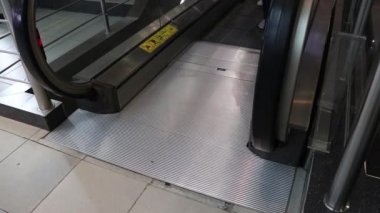 Alışveriş merkezindeki siyah merdiven yürüyen merdiven. Sosyal mesafeyi korumak için ayak izi işareti var.