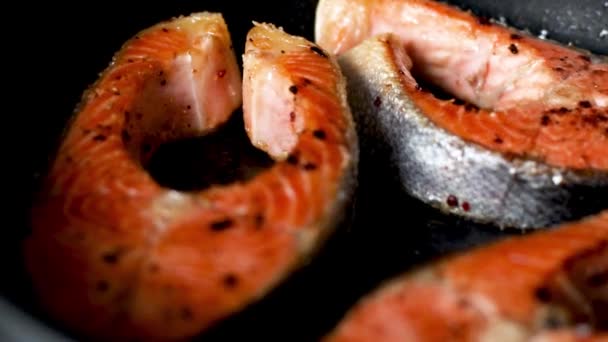 Memasak steak salmon dengan rempah-rempah dalam panci hitam. Close-up. — Stok Video