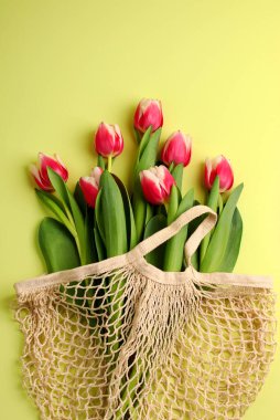 Bahar konsepti, bir buket lale çiçeği hafif bir arka planda ip torbasında. Kadınlar günü, sevgililer günü konsepti, anneler günü. Çevre ambalajı. Dikey pozisyonda. Düz yatıyordu.