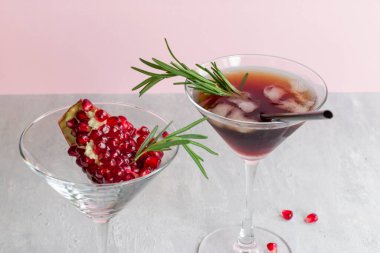 Açık pembe arka planda biberiyeli alkolsüz nar kokteyli. Bardakta meyve taneleri. Doğal sağlıklı içecek..