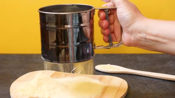 Las manos del chef tamizan la harina de maíz sobre una tabla de madera, maíz fresco sobre un fondo amarillo. El concepto de la producción de productos a partir del maíz. — Vídeos de Stock